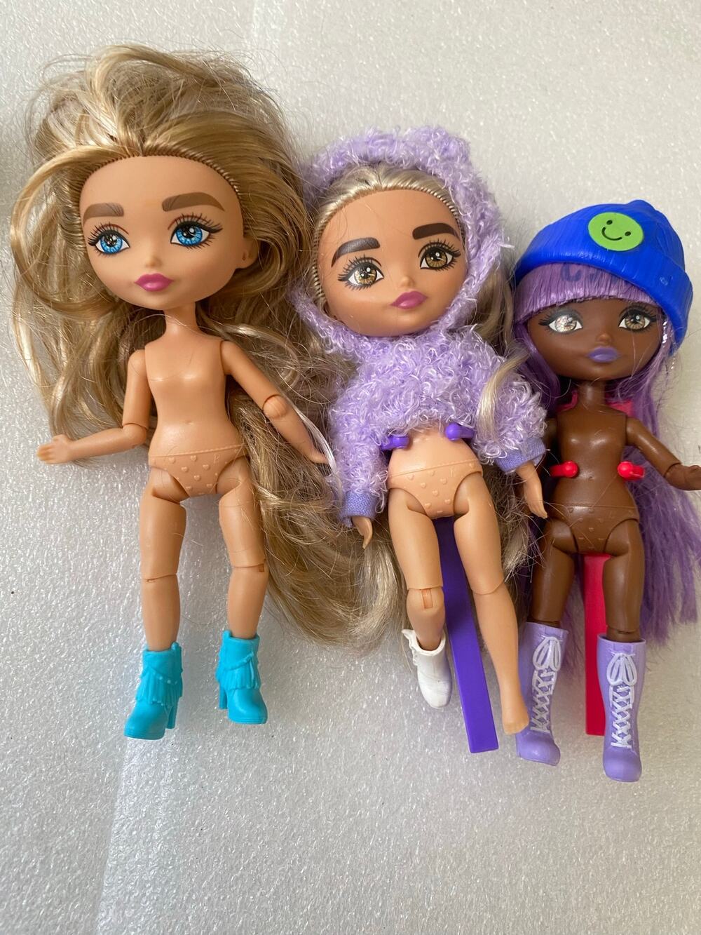 three Mattel Barbie Extra Minis fashion dolls in partial outfits and stands